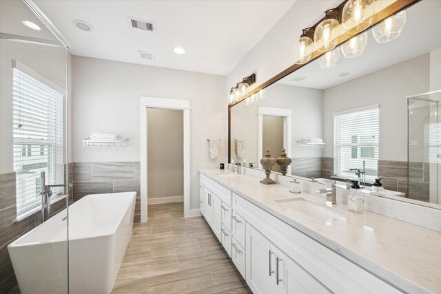 1226 W 17th St Unit E, Houston, TX 77008 - full bath with double vanity, a freestanding tub, an enclosed shower, baseboards, and tile walls