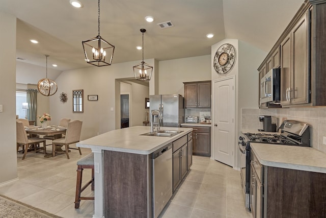 kitchen featuring appliances with stainless steel finishes, vaulted ceiling, a sink, light countertops, and tasteful backsplash
