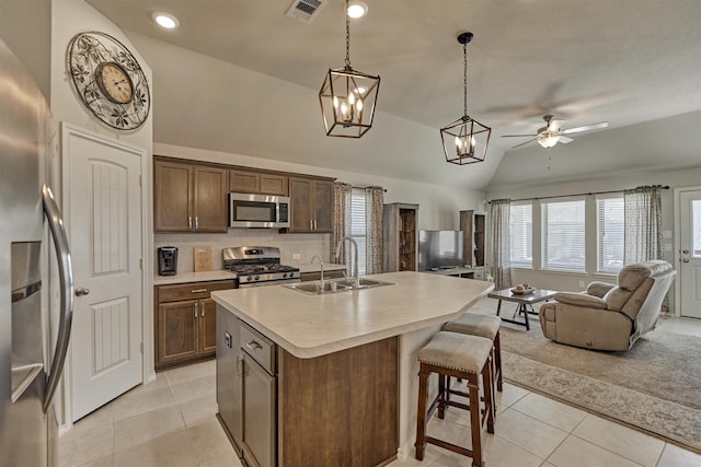 kitchen featuring appliances with stainless steel finishes, a sink, light tile patterned flooring, open floor plan, and a ceiling fan