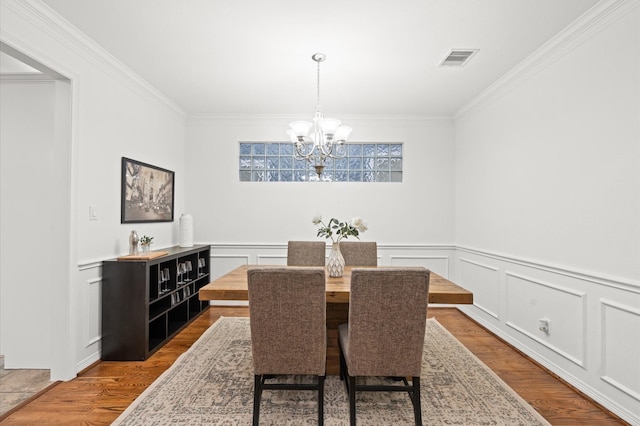 1117 Beall Landing Ct, Houston, TX 77008 - dining room with crown molding, a chandelier, wood finished floors, wainscoting, and a decorative wall
