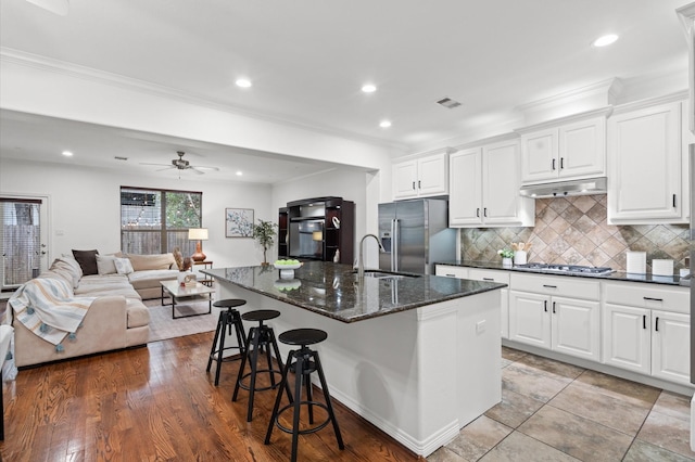 1117 Beall Landing Ct, Houston, TX 77008 - kitchen featuring appliances with stainless steel finishes, a sink, under cabinet range hood, open floor plan, and a breakfast bar