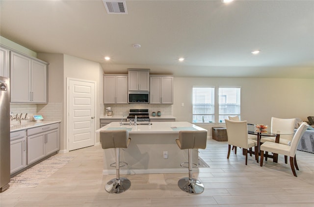 12917 S Winding Pines Dr, Tomball, TX 77375 - kitchen with appliances with stainless steel finishes, light countertops, backsplash, recessed lighting, and an island with sink