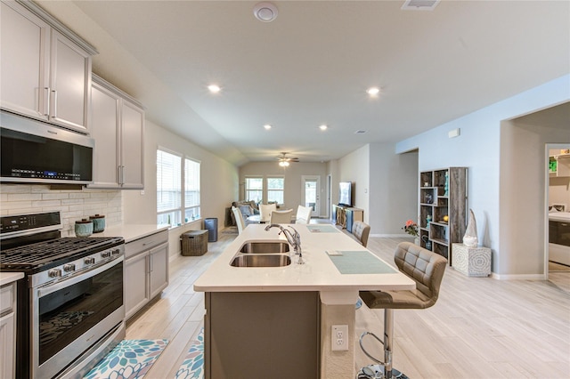 12917 S Winding Pines Dr, Tomball, TX 77375 - kitchen featuring appliances with stainless steel finishes, a sink, open floor plan, light wood-type flooring, and gray cabinets