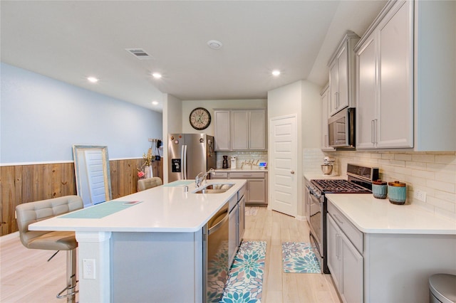 12917 S Winding Pines Dr, Tomball, TX 77375 - kitchen featuring stainless steel appliances, a sink, a breakfast bar area, light wood finished floors, and a kitchen island with sink