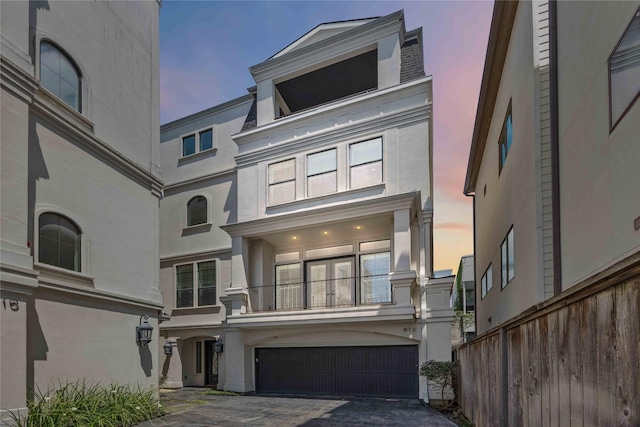 812 W Drew St, Houston, TX 77006 - view of front of house featuring stucco siding, a garage, fence, a balcony, and driveway