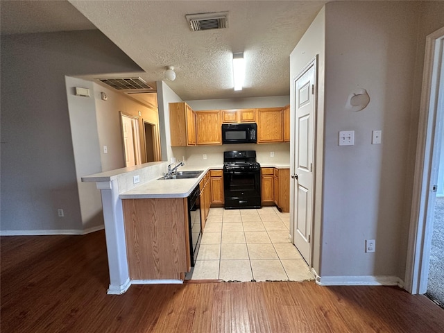 6723 Highwind Bend Ln, Katy, TX 77449 - kitchen featuring black appliances, a sink, a peninsula, light countertops, and light wood finished floors