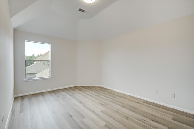 unfurnished room featuring light wood-style floors, vaulted ceiling, and baseboards