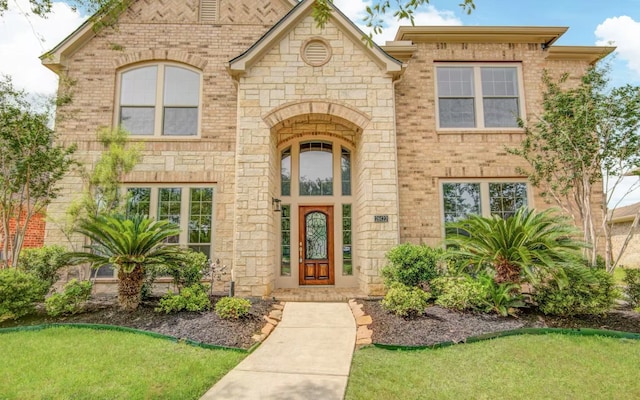 doorway to property with brick siding, stone siding, and a lawn