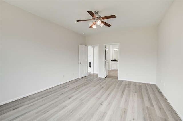 unfurnished bedroom featuring light wood-style floors, baseboards, ensuite bath, and a ceiling fan