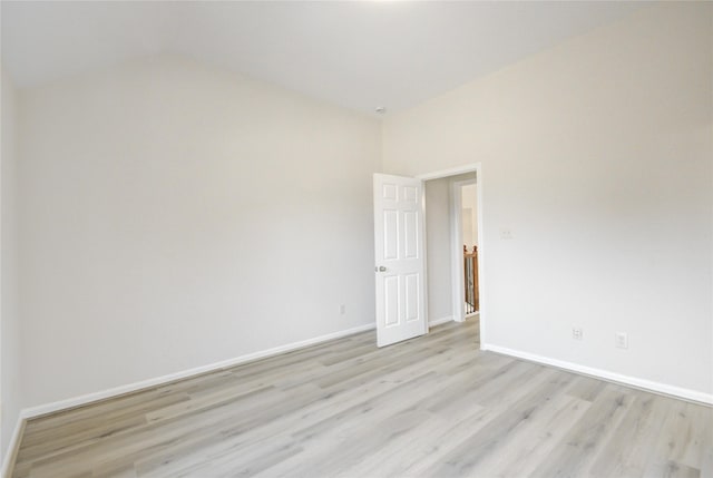 unfurnished room with light wood finished floors, baseboards, and vaulted ceiling