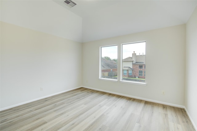empty room featuring light wood-style flooring, lofted ceiling, and baseboards