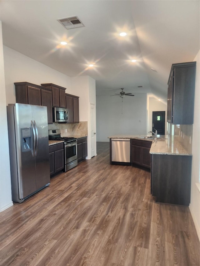 23716 Wood Green Terrace Dr, New Caney, TX 77357 - kitchen with appliances with stainless steel finishes, a ceiling fan, lofted ceiling, dark brown cabinetry, and light stone counters