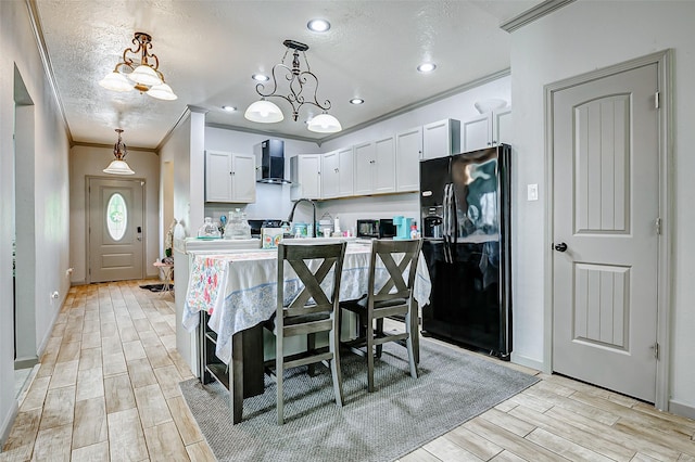 873 W Santa Fe St, Conroe, TX 77301 - kitchen featuring black appliances, wall chimney exhaust hood, ornamental molding, light wood-type flooring, and white cabinetry