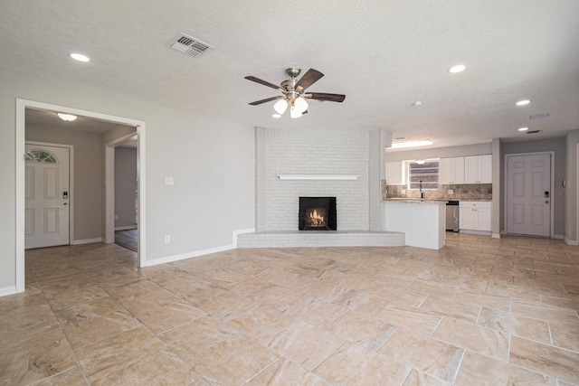 10056 Woodhollow Dr, Conroe, TX 77385 - unfurnished living room featuring ceiling fan, recessed lighting, baseboards, a brick fireplace, and a textured ceiling