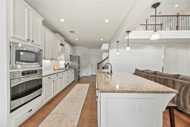 9210 Cold Hollow Ln, Missouri City, TX 77459 - kitchen featuring stainless steel appliances, a sink, white cabinets, an island with sink, and recessed lighting