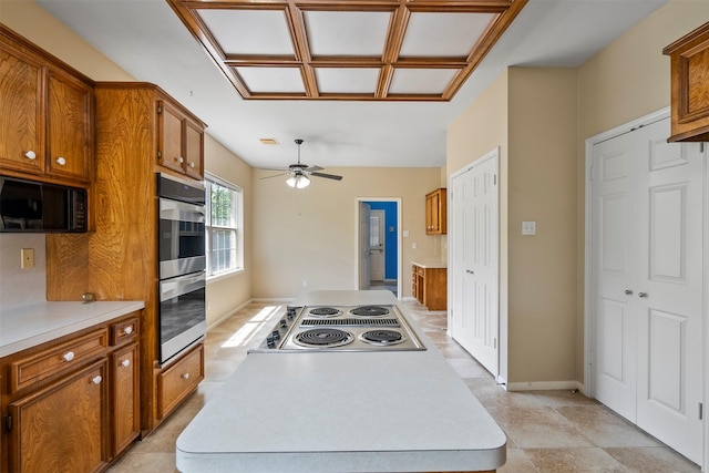 21735 Cayman Point Dr, Katy, TX 77450 - kitchen with appliances with stainless steel finishes, light countertops, brown cabinets, a center island, and a ceiling fan