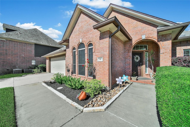 61 Chicory Ct, Lake Jackson, TX 77566 - doorway to property with an attached garage, driveway, brick siding, and central air condition unit