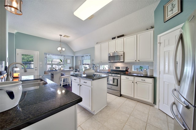 61 Chicory Ct, Lake Jackson, TX 77566 - kitchen with appliances with stainless steel finishes, a sink, vaulted ceiling, white cabinetry, and a center island