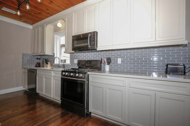 4434 Leeland St, Houston, TX 77023 - kitchen featuring stainless steel appliances, a sink, light countertops, dark wood-type flooring, and crown molding