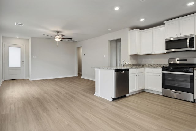 15842 Berry Hill Dr, Conroe, TX 77303 - kitchen with stainless steel appliances, a peninsula, ceiling fan, baseboards, and white cabinets