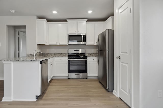 15842 Berry Hill Dr, Conroe, TX 77303 - kitchen with appliances with stainless steel finishes, a sink, white cabinets, a peninsula, and recessed lighting
