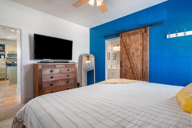2932 Lakeside Dr, Crystal Beach, TX 77650 - bedroom with light wood-style flooring, connected bathroom, a barn door, and ceiling fan