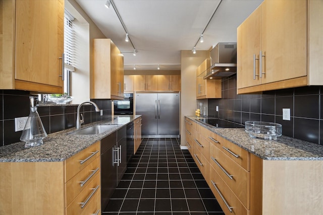 kitchen featuring a sink, track lighting, black appliances, wall chimney exhaust hood, and backsplash