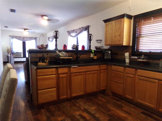 413 Paulus St, Schulenburg, TX 78956 - kitchen with dark wood finished floors, a peninsula, dark countertops, a ceiling fan, and decorative backsplash