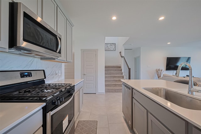 28923 Yukon River Ct, Katy, TX 77494 - kitchen with stainless steel appliances, a sink, gray cabinets, recessed lighting, and decorative backsplash