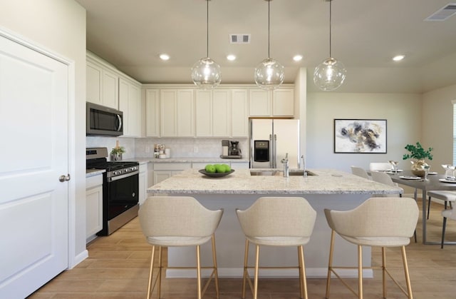 3217 21st St N, Texas City, TX 77590 - kitchen with stainless steel appliances, a sink, recessed lighting, a center island with sink, and light wood-type flooring