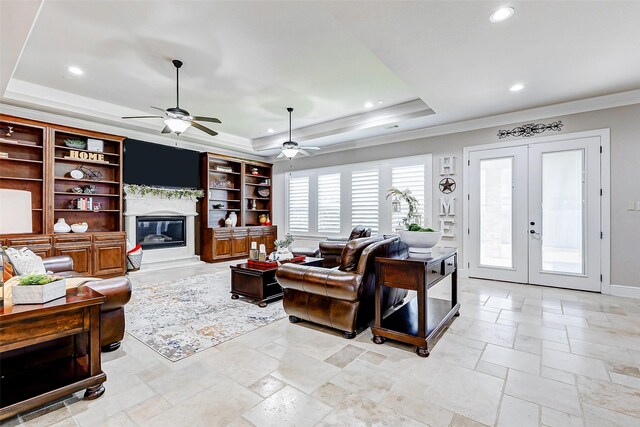 32811 Warbler Ct, Fulshear, TX 77441 - living room with a tray ceiling, ornamental molding, a glass covered fireplace, recessed lighting, and ceiling fan