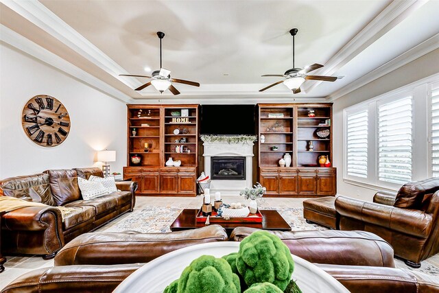 32811 Warbler Ct, Fulshear, TX 77441 - living area with a tray ceiling, ceiling fan, crown molding, a glass covered fireplace, and built in features