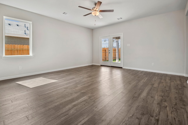 spare room with dark wood-type flooring, a ceiling fan, and baseboards