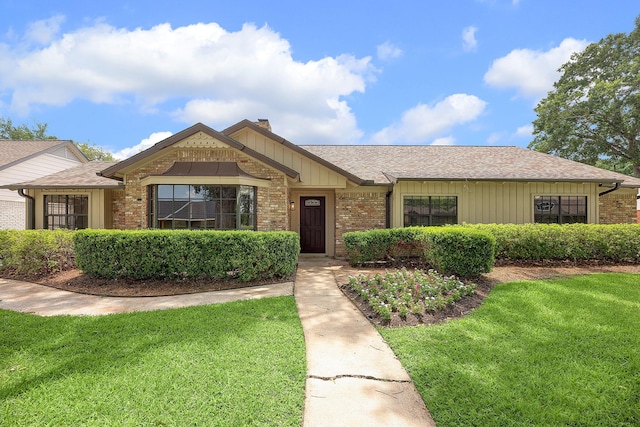 ranch-style house featuring brick siding, a front lawn, a chimney, and a shingled roof
