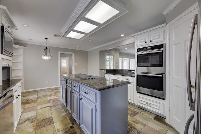 kitchen featuring appliances with stainless steel finishes, crown molding, stone tile flooring, white cabinets, and a kitchen island