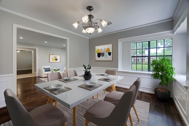 dining space featuring a chandelier, a wainscoted wall, ornamental molding, dark wood-style flooring, and a decorative wall