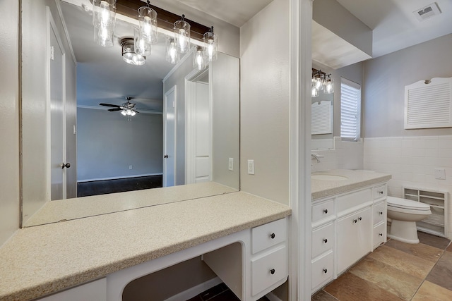bathroom featuring vanity, toilet, a ceiling fan, and tile walls
