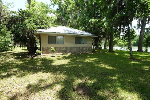 215 Weldon, Livingston, TX 77351 - view of home's exterior with stone siding, a yard, metal roof, and a water view