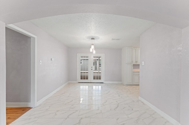 6105 Arthington St, Houston, TX 77053 - unfurnished dining area featuring light marble finish flooring, baseboards, french doors, and a textured ceiling