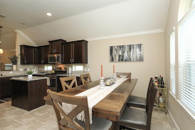 dining room featuring vaulted ceiling, light tile patterned flooring, and crown molding