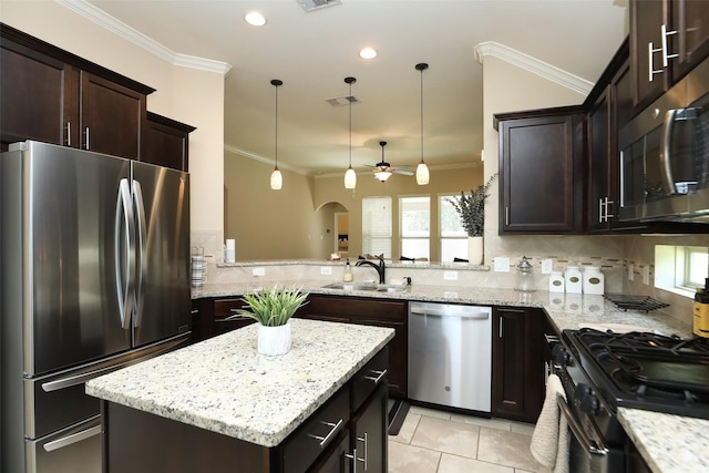 kitchen with appliances with stainless steel finishes, crown molding, a sink, dark brown cabinets, and light stone countertops