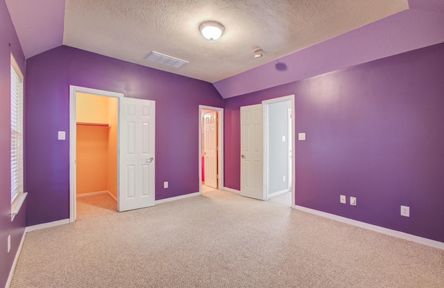 10711 Sea Myrtle Dr, Houston, TX 77095 - unfurnished bedroom with lofted ceiling, a spacious closet, baseboards, a textured ceiling, and carpet flooring