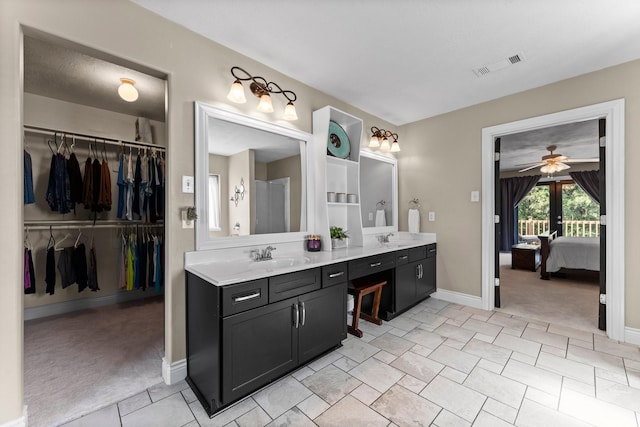 32123 Willow Creek Park, Conroe, TX 77385 - bathroom featuring connected bathroom, baseboards, vanity, ceiling fan, and a walk in closet