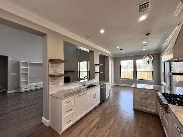 kitchen with a sink, stainless steel dishwasher, open floor plan, baseboards, and crown molding