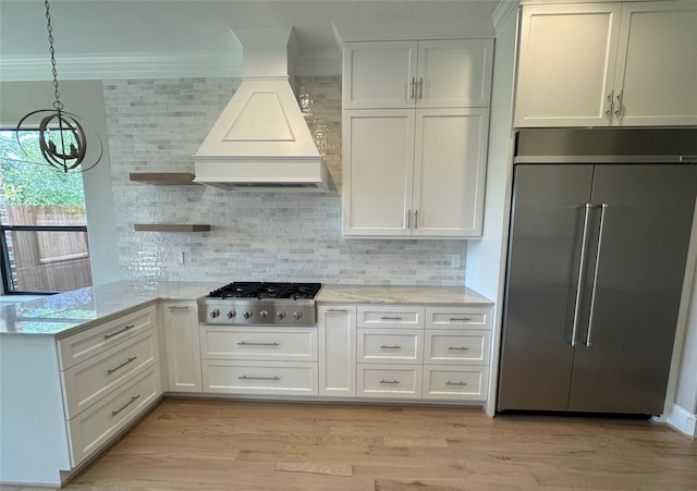 kitchen with built in refrigerator, premium range hood, stainless steel gas cooktop, ornamental molding, and open shelves
