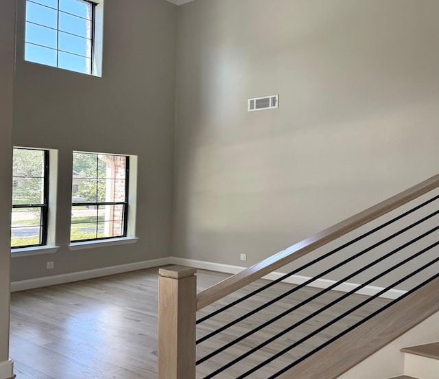 staircase with wood finished floors, baseboards, and a high ceiling