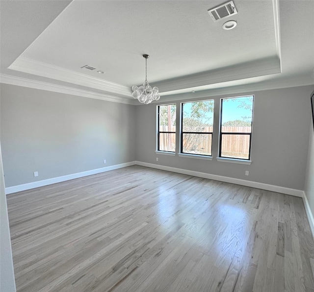 unfurnished dining area featuring a raised ceiling, ornamental molding, light wood finished floors, and a chandelier