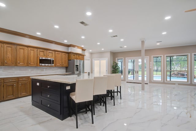 2616 Ryder Ct, League City, TX 77573 - kitchen with stainless steel appliances, light marble finish floors, crown molding, brown cabinets, and decorative backsplash
