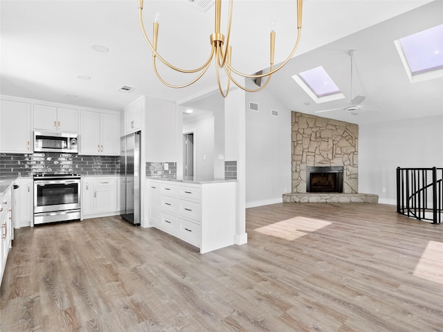 1322 Oahu Dr, Tiki Island, TX 77554 - kitchen featuring appliances with stainless steel finishes, a skylight, open floor plan, white cabinetry, and lofted ceiling