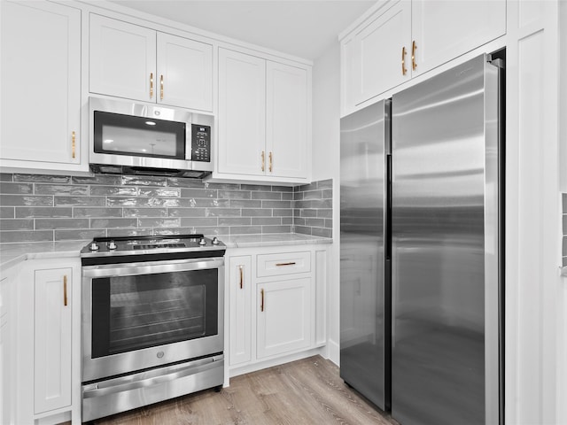 1322 Oahu Dr, Tiki Island, TX 77554 - kitchen with appliances with stainless steel finishes, white cabinets, tasteful backsplash, light wood finished floors, and light stone countertops